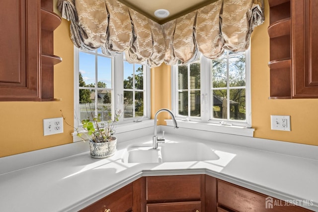 room details featuring open shelves, brown cabinetry, light countertops, and a sink