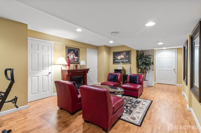 living area with light wood finished floors, recessed lighting, a fireplace, and baseboards