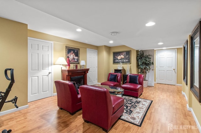 living area featuring recessed lighting, baseboards, light wood-style floors, and a fireplace