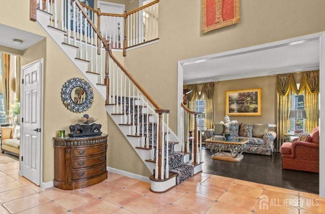 stairway featuring tile patterned flooring, a healthy amount of sunlight, and baseboards