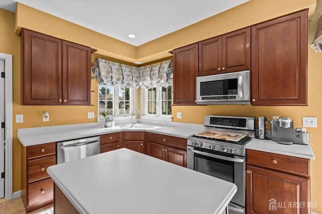 kitchen with a sink, stainless steel appliances, a kitchen island, and light countertops