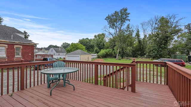 wooden terrace featuring a garage, an outdoor structure, and a yard