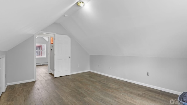 bonus room with lofted ceiling, a baseboard heating unit, and dark hardwood / wood-style floors