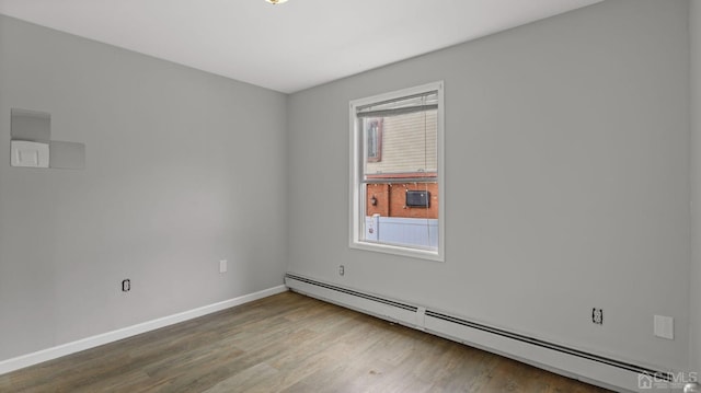 empty room featuring hardwood / wood-style flooring and a baseboard heating unit