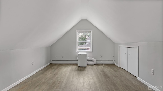 additional living space featuring vaulted ceiling, hardwood / wood-style floors, and baseboard heating