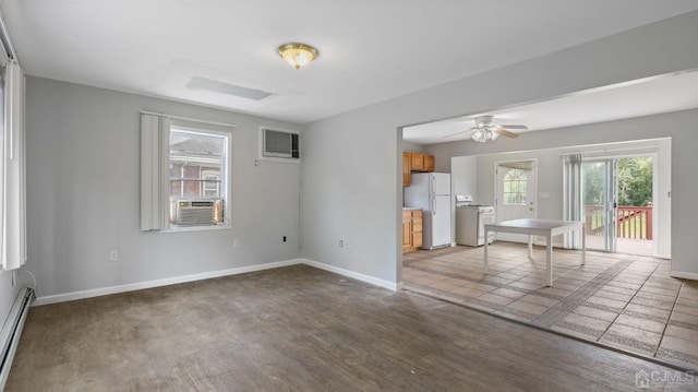 unfurnished room with a wall mounted air conditioner, washer / dryer, hardwood / wood-style flooring, ceiling fan, and baseboard heating