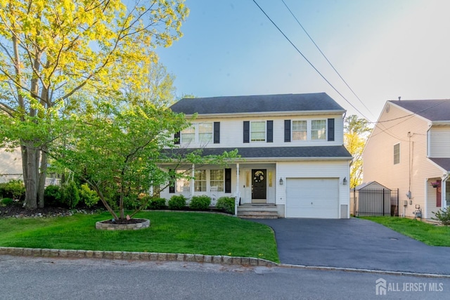 traditional-style home with a garage, a front lawn, and aphalt driveway