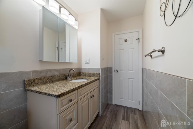 bathroom with hardwood / wood-style floors, vanity, and tile walls