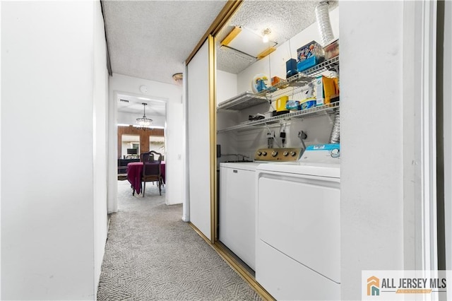 clothes washing area featuring laundry area, separate washer and dryer, a textured ceiling, and light colored carpet