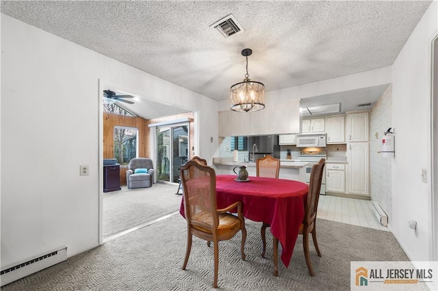 dining space with a baseboard heating unit, visible vents, light carpet, and a textured ceiling