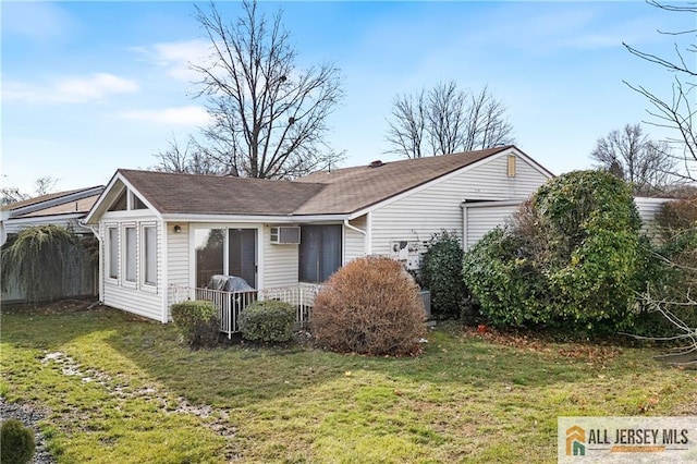 exterior space with a front lawn and a wall unit AC