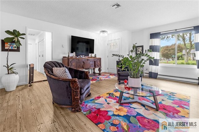 275 Convent Rd Unit 275A, Monroe, NJ 08831 - living room with wood finished floors, a baseboard radiator, and a textured ceiling