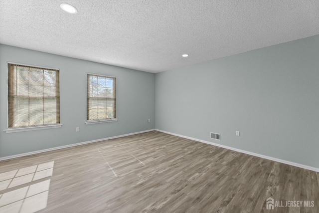 spare room featuring baseboards, visible vents, and wood finished floors