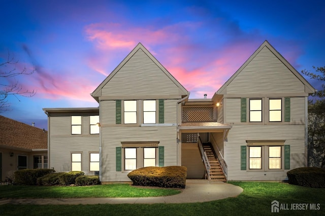 view of front facade with stairway and a front lawn