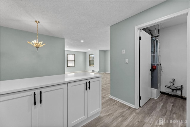 kitchen featuring light countertops, hanging light fixtures, light wood-style flooring, and white cabinetry