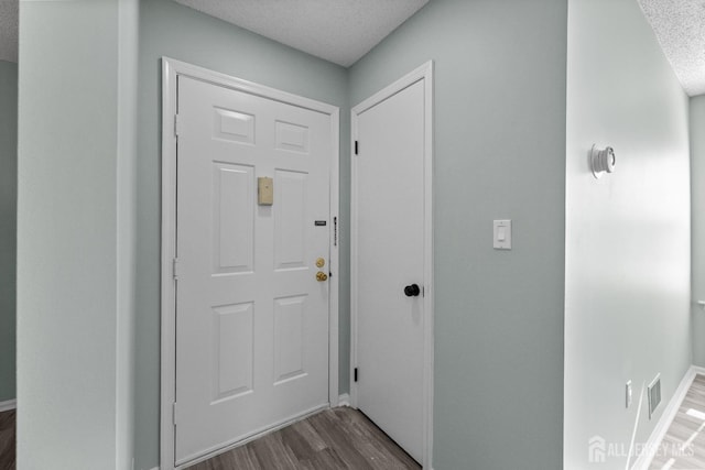 entryway with a textured ceiling and wood finished floors