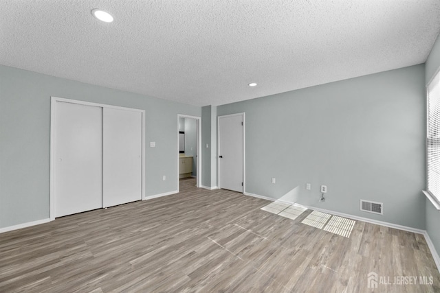 unfurnished bedroom featuring baseboards, visible vents, and wood finished floors