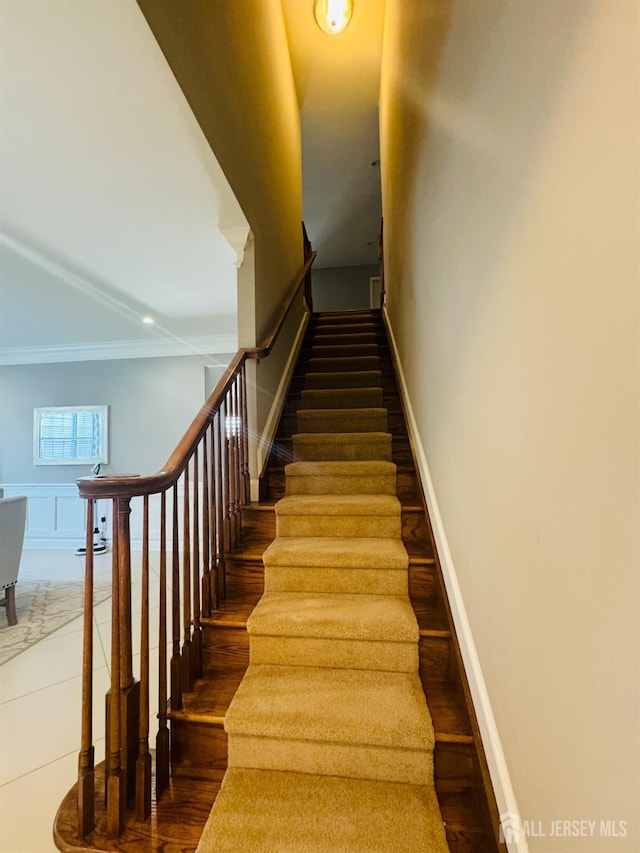 stairway with baseboards, ornamental molding, and wood finished floors