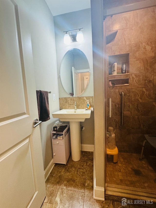 full bath with baseboards and tiled shower