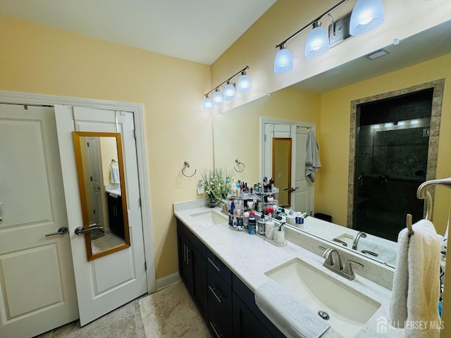full bathroom with double vanity, baseboards, a sink, and a stall shower