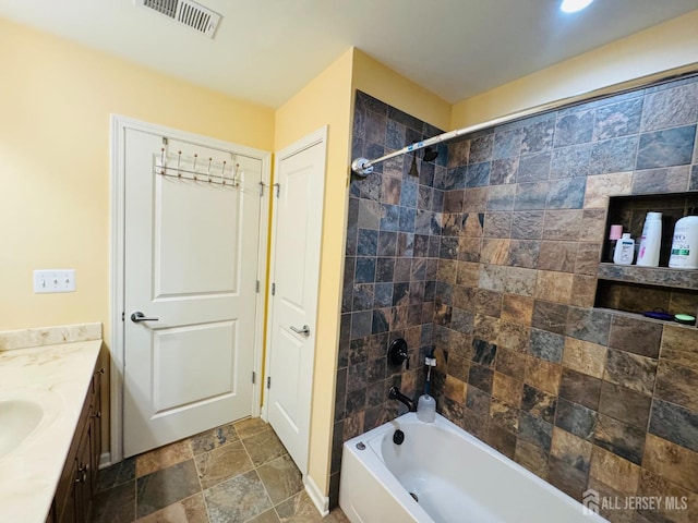 bathroom with vanity, shower / bath combination, visible vents, and stone tile flooring