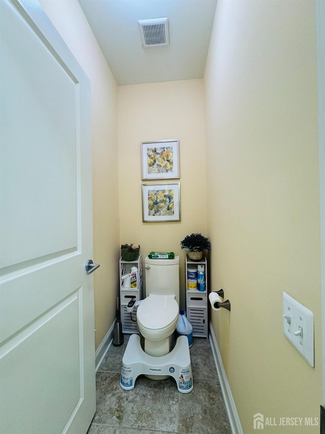 bathroom with baseboards, toilet, and visible vents