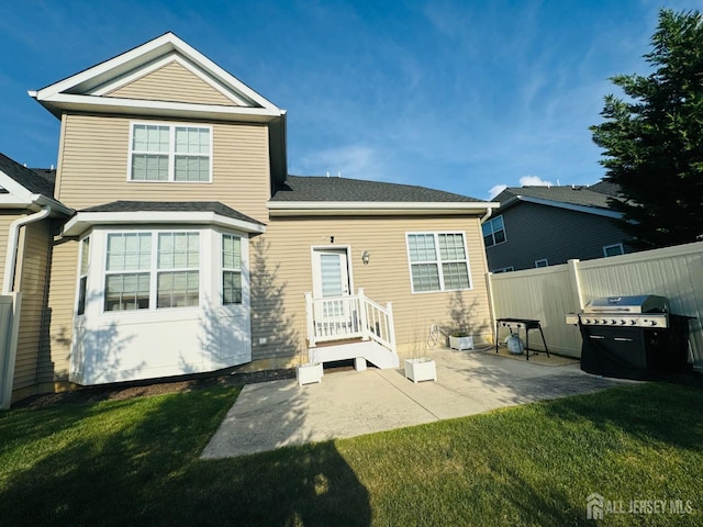 back of property featuring fence, a patio, and a lawn