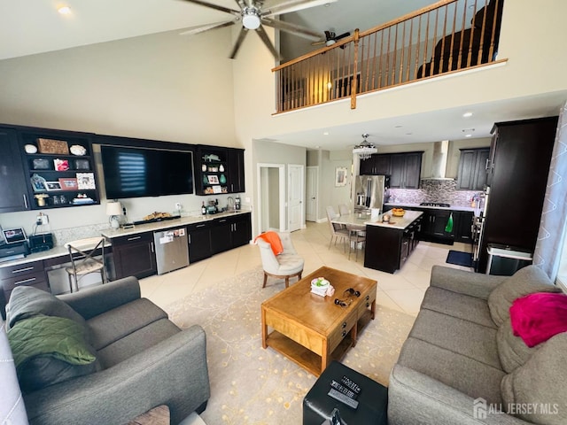 living room with high vaulted ceiling, indoor wet bar, a ceiling fan, and light tile patterned flooring