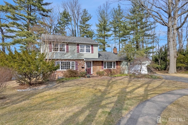 view of front facade featuring a garage, a chimney, aphalt driveway, a front lawn, and brick siding