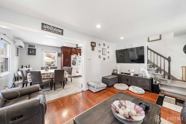 living room with ceiling fan, a wall unit AC, a healthy amount of sunlight, and light wood-type flooring