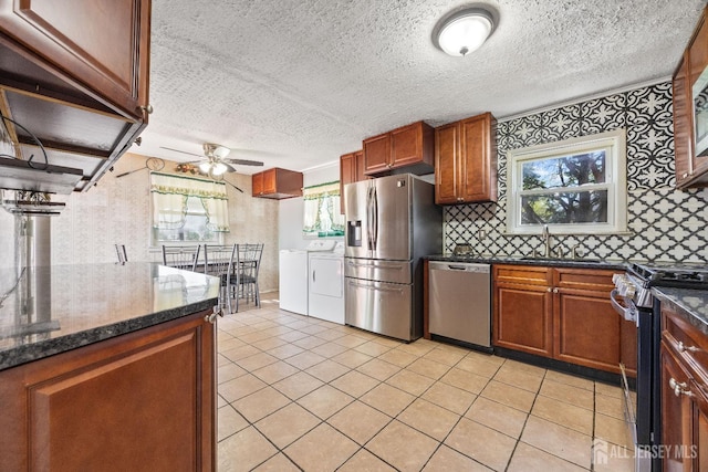 kitchen with independent washer and dryer, stainless steel appliances, ceiling fan, a sink, and a textured ceiling