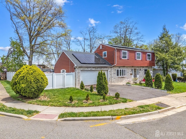 view of front of property with solar panels, an attached garage, and asphalt driveway