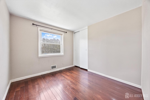 empty room featuring dark wood-type flooring and baseboards