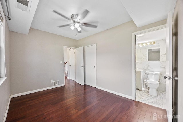 unfurnished bedroom with hardwood / wood-style floors, baseboards, a closet, connected bathroom, and ceiling fan