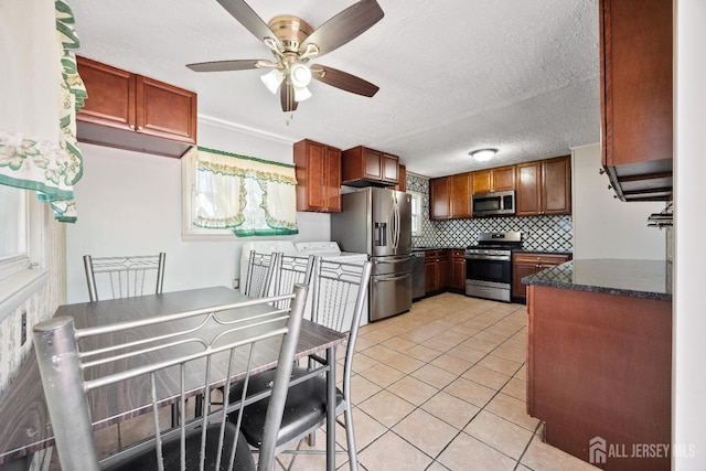 kitchen with stainless steel appliances, ceiling fan, backsplash, light tile patterned flooring, and a textured ceiling