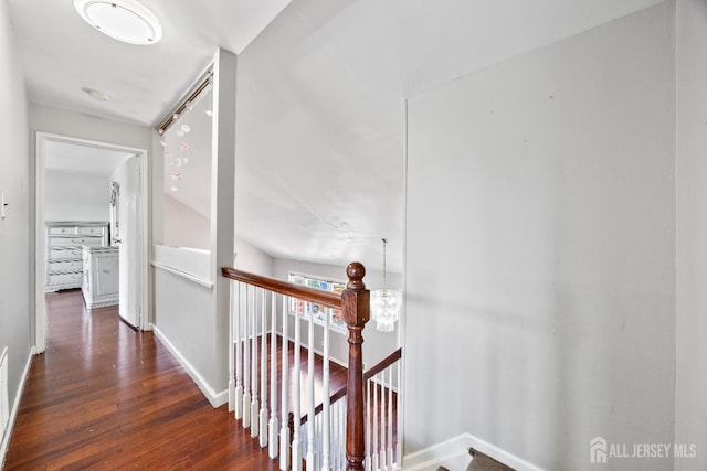 corridor featuring an upstairs landing, wood finished floors, and baseboards