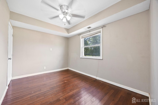 unfurnished room featuring hardwood / wood-style floors, baseboards, ceiling fan, and a tray ceiling