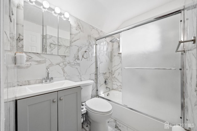 full bathroom featuring marble finish flooring, toilet, tile walls, vanity, and bath / shower combo with glass door
