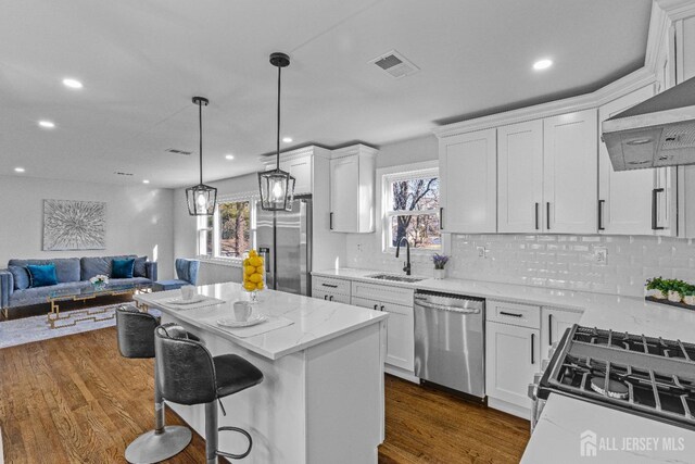 kitchen with a kitchen island, stainless steel appliances, white cabinets, and sink