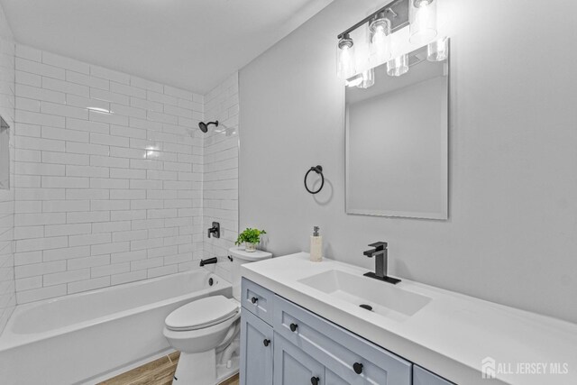 full bathroom with tiled shower / bath, toilet, vanity, and hardwood / wood-style flooring