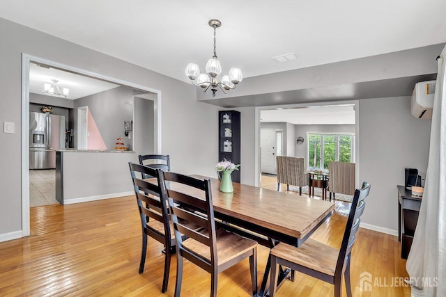 dining space featuring baseboards, light wood finished floors, and a chandelier