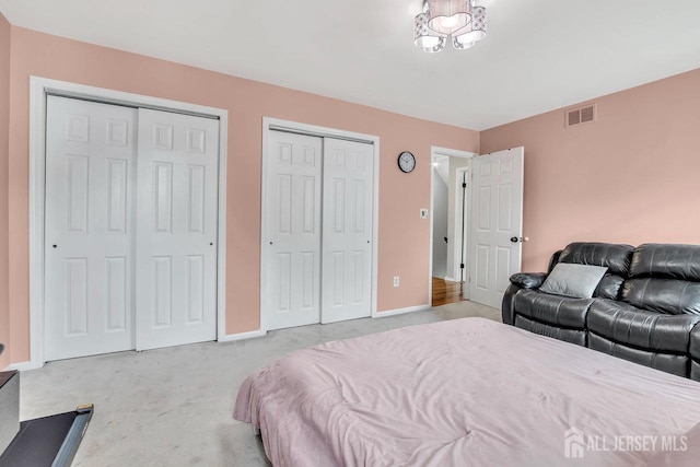 carpeted bedroom featuring multiple closets, baseboards, and visible vents