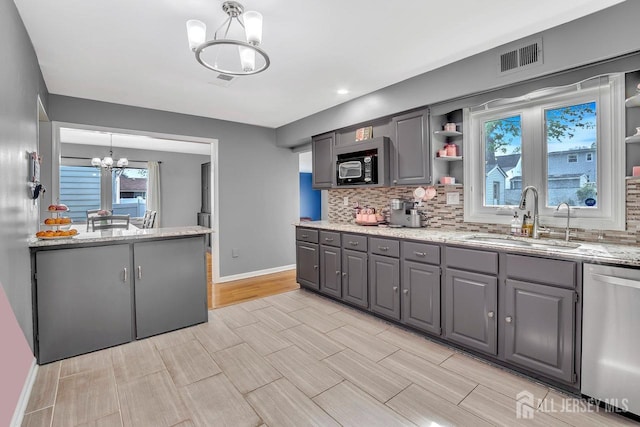 kitchen with stainless steel dishwasher, a sink, a notable chandelier, and gray cabinetry