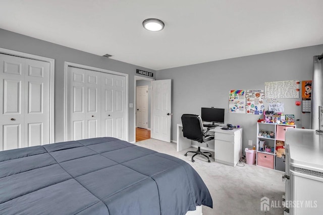 bedroom with carpet, two closets, and visible vents