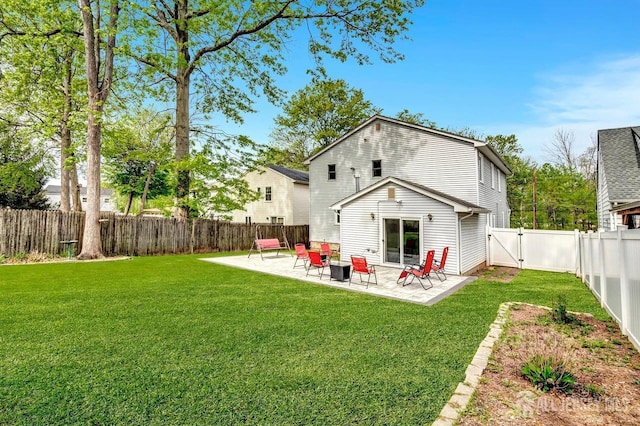 back of house featuring a patio, a fenced backyard, a lawn, and a gate