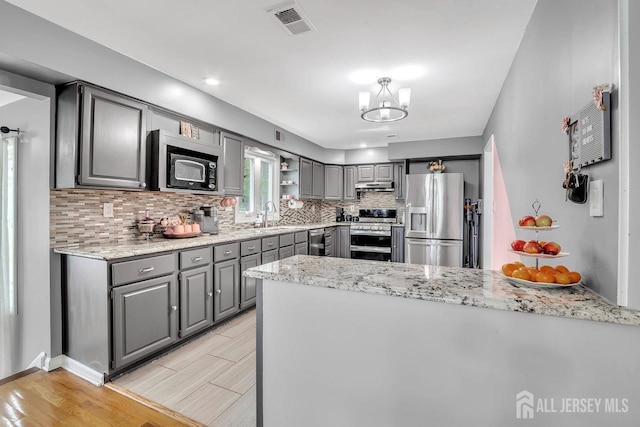 kitchen with decorative backsplash, gray cabinets, visible vents, stainless steel appliances, and under cabinet range hood