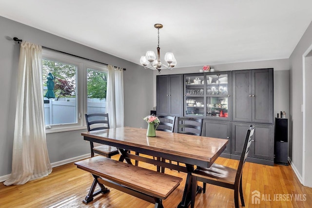 dining room with baseboards, light wood-type flooring, and a chandelier