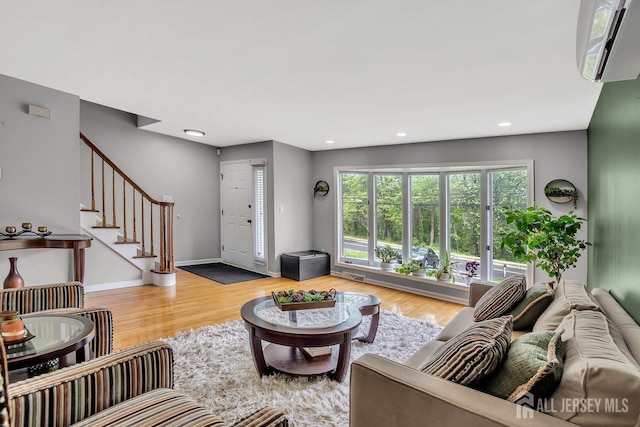living area featuring an AC wall unit, recessed lighting, baseboards, wood finished floors, and stairway