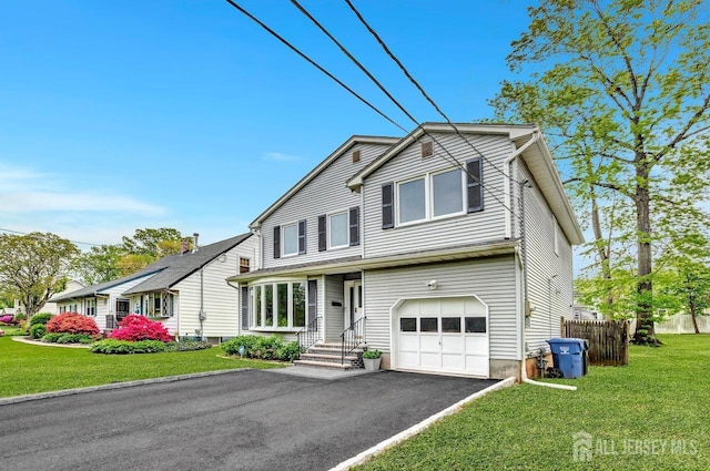 traditional-style home with a garage, fence, a front lawn, and aphalt driveway