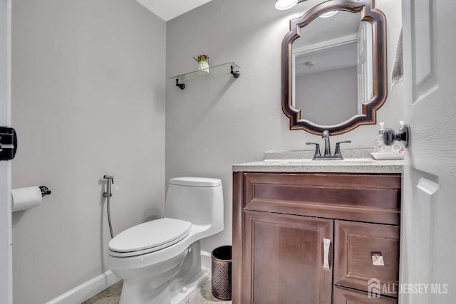 bathroom with toilet, baseboards, and vanity